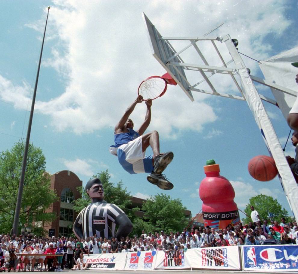 Tracy 'Supernintendo' Turner of Silver Spring, MD. hangs onto the rim after a slam dunk in the Hoop it Up Slam Dunk Contest at Festival Park, 1995