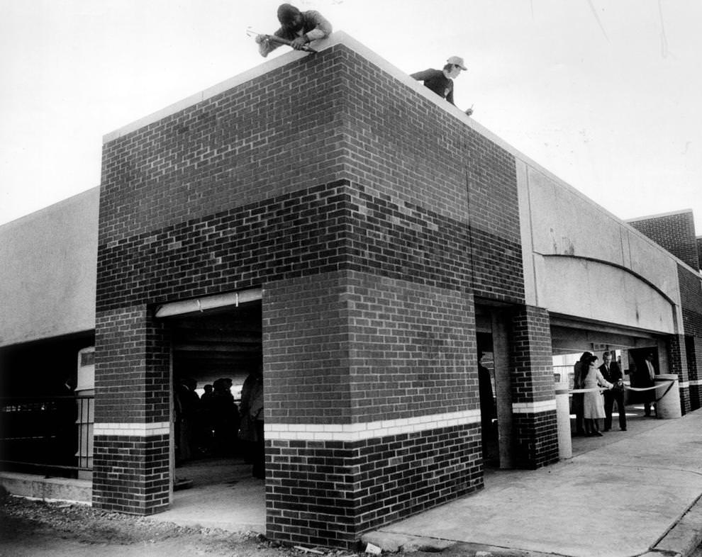 Chamberlayne Co. Inc. workers Wesley Boyette and Craig Simpson put finishing touches on a parking garage in Richmond’s Carytown area while the ribbon-cutting ceremony for the Crenshaw Avenue facility was held at street level, 1991.