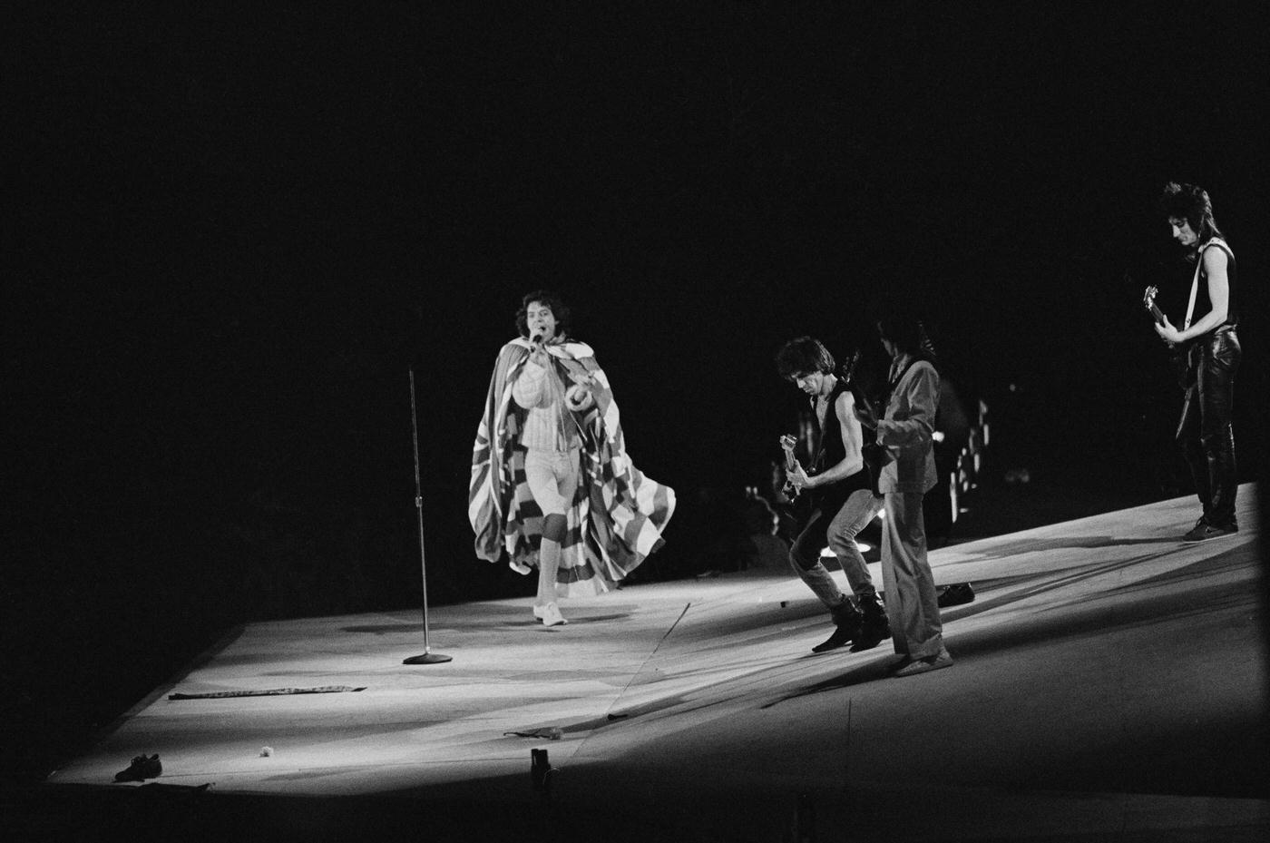 Mick Jagger, draped in an American flag, performs with Keith Richards, Bill Wyman, and Ronnie Wood , 1975.