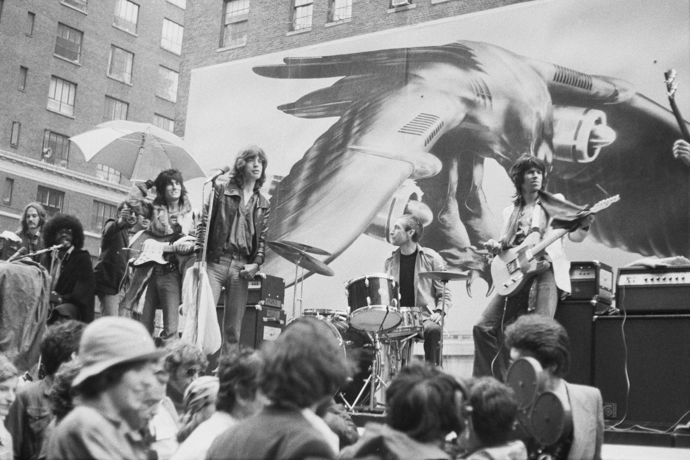 Billy Preston, Ronnie Wood, Mick Jagger, Charlie Watts, and Keith Richards perform on a flatbed truck on Fifth Avenue, New York City, 1975.