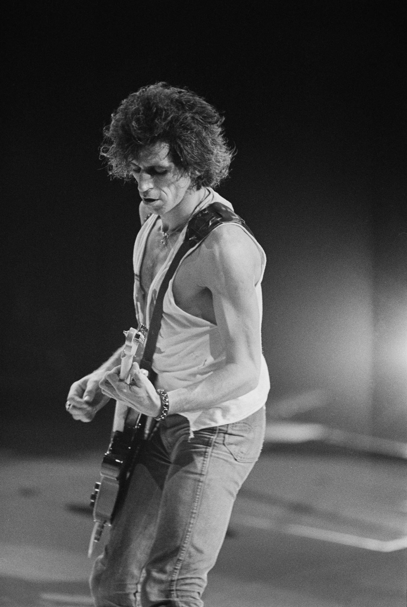 Keith Richards, wearing a ripped vest, performs with The Rolling Stones , 1975.