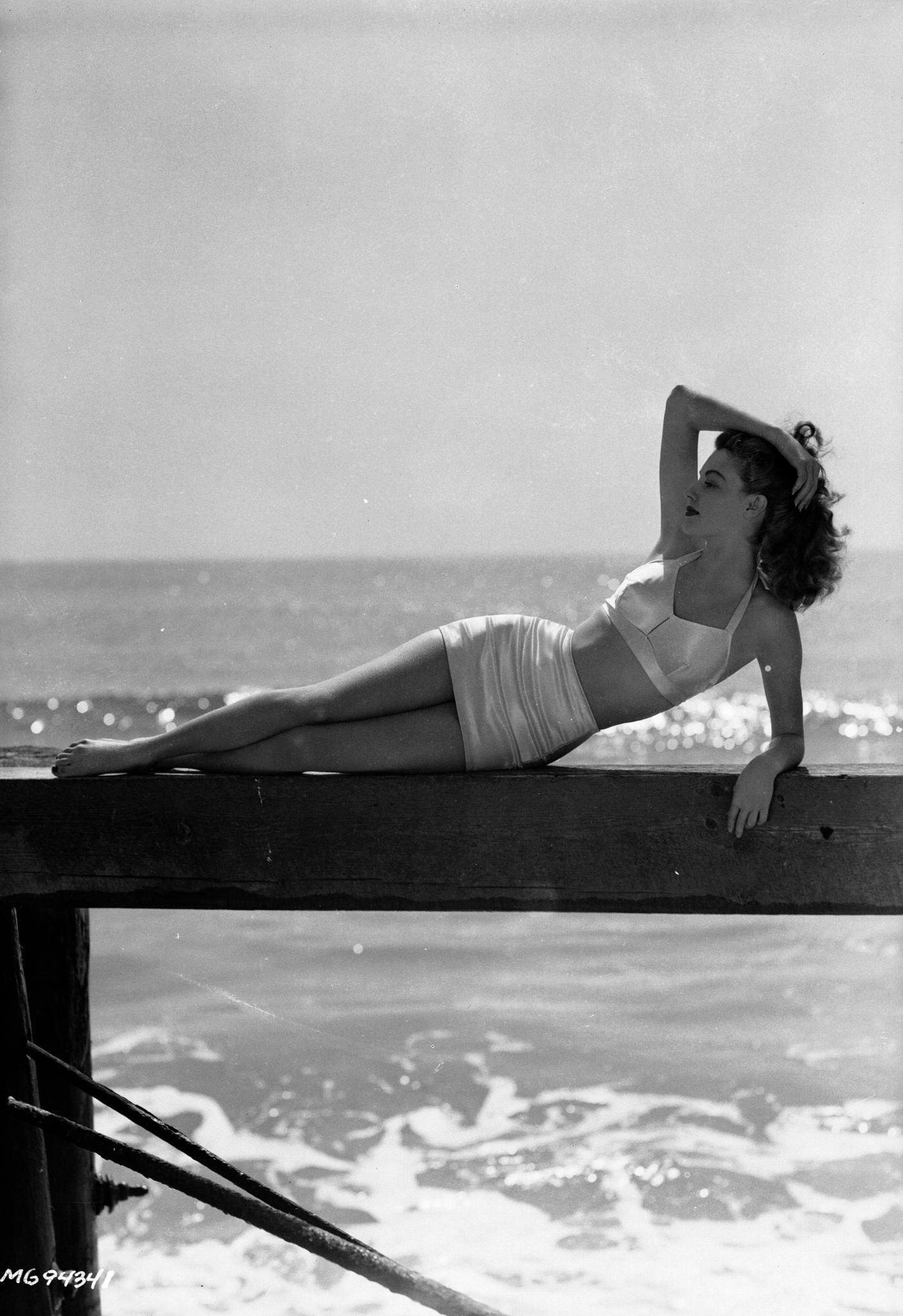 Actress Ava Gardner lounging on a wooden jetty in an elegant bikini, March 1943.