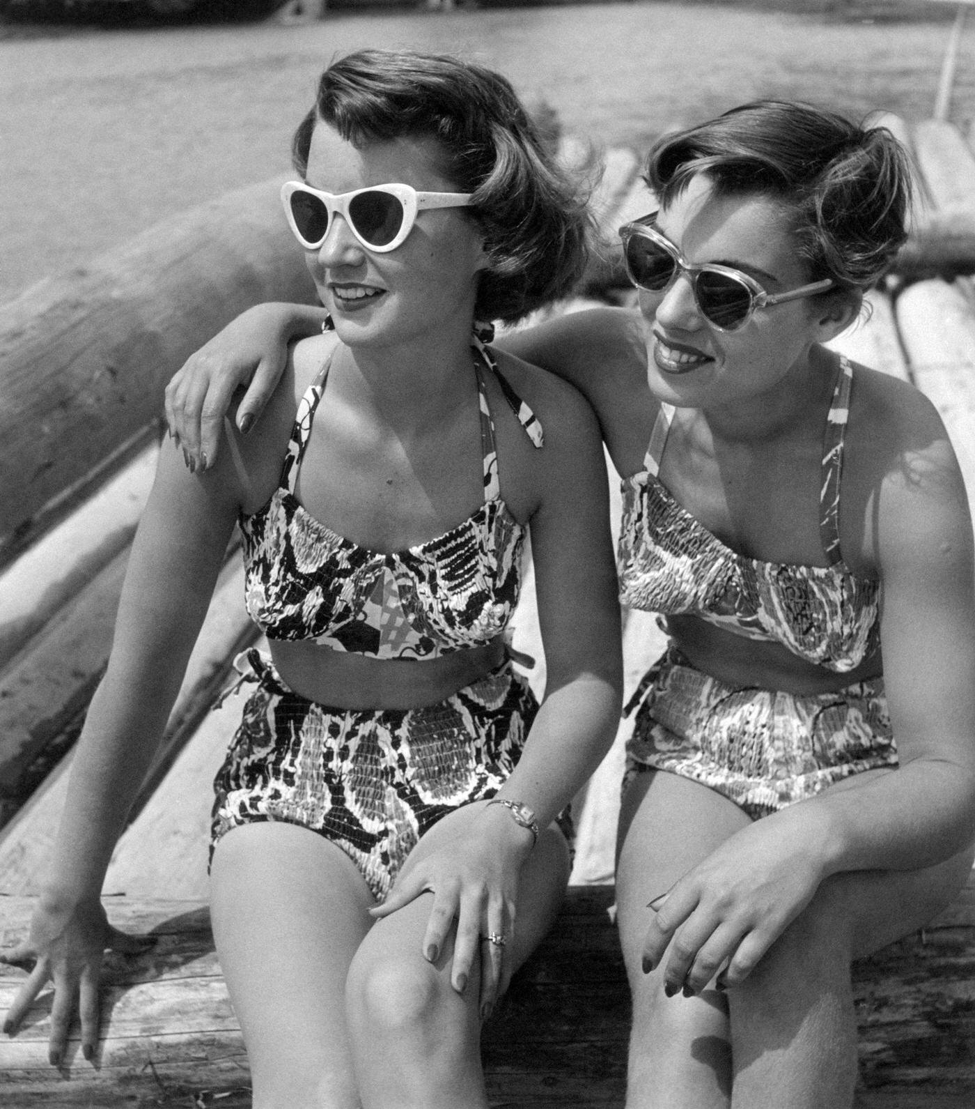 Two girls in sunglasses and bikini hugging each other, 1950s.
