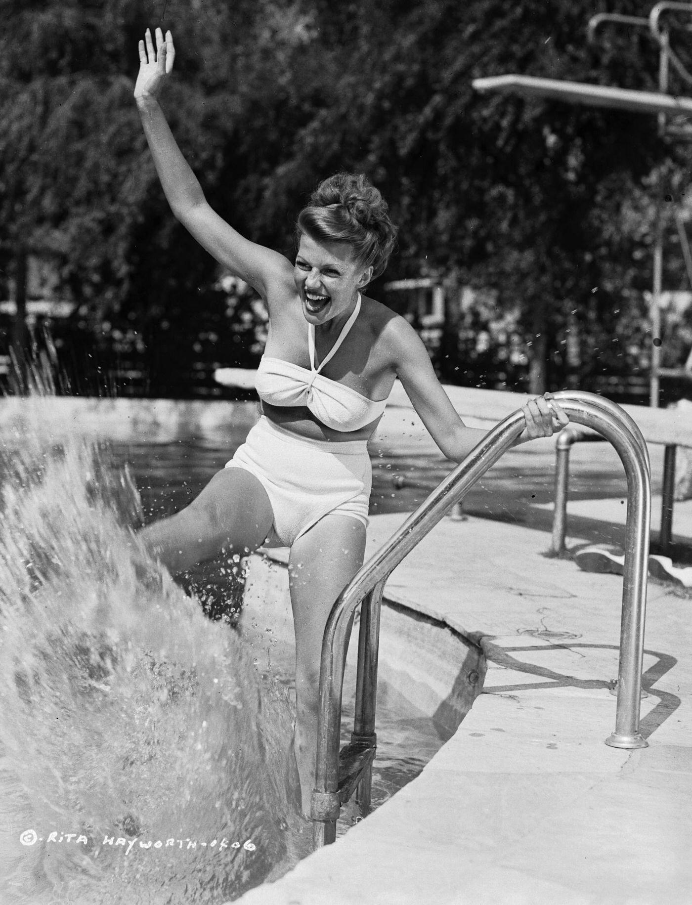 Rita Hayworth splashing the surface of a swimming pool, circa 1946.