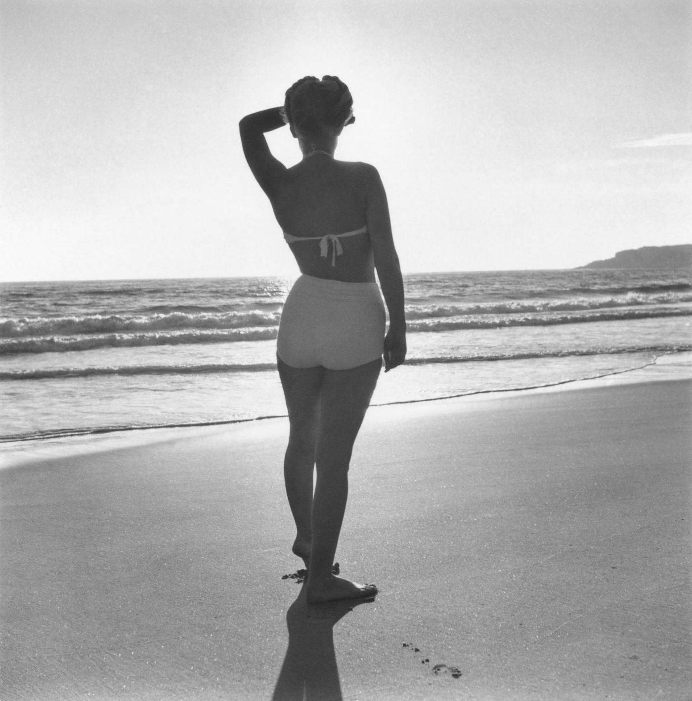 Marilyn Monroe posing on a beach in a two-piece swimsuit, Malibu, California, 1946.