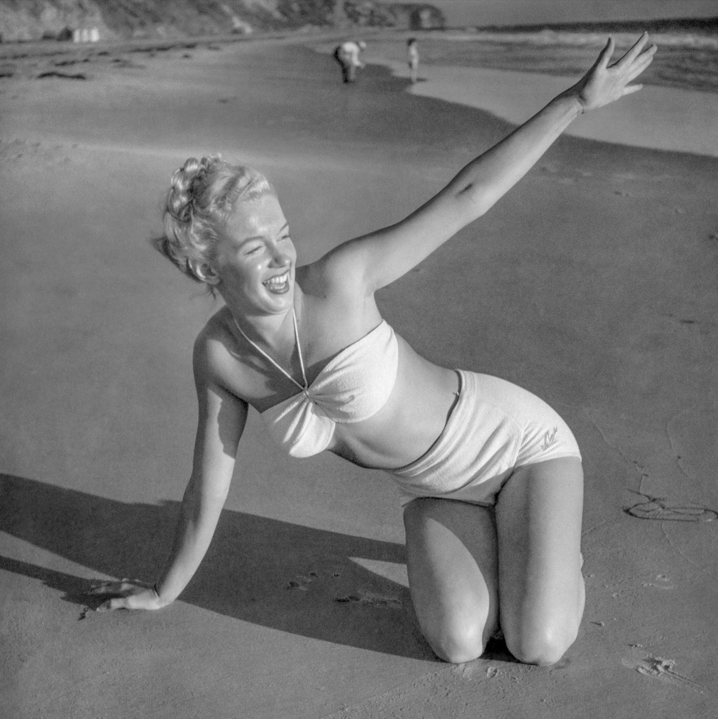 Marilyn Monroe posing on a beach in a two-piece swimsuit, Malibu, California, 1946.