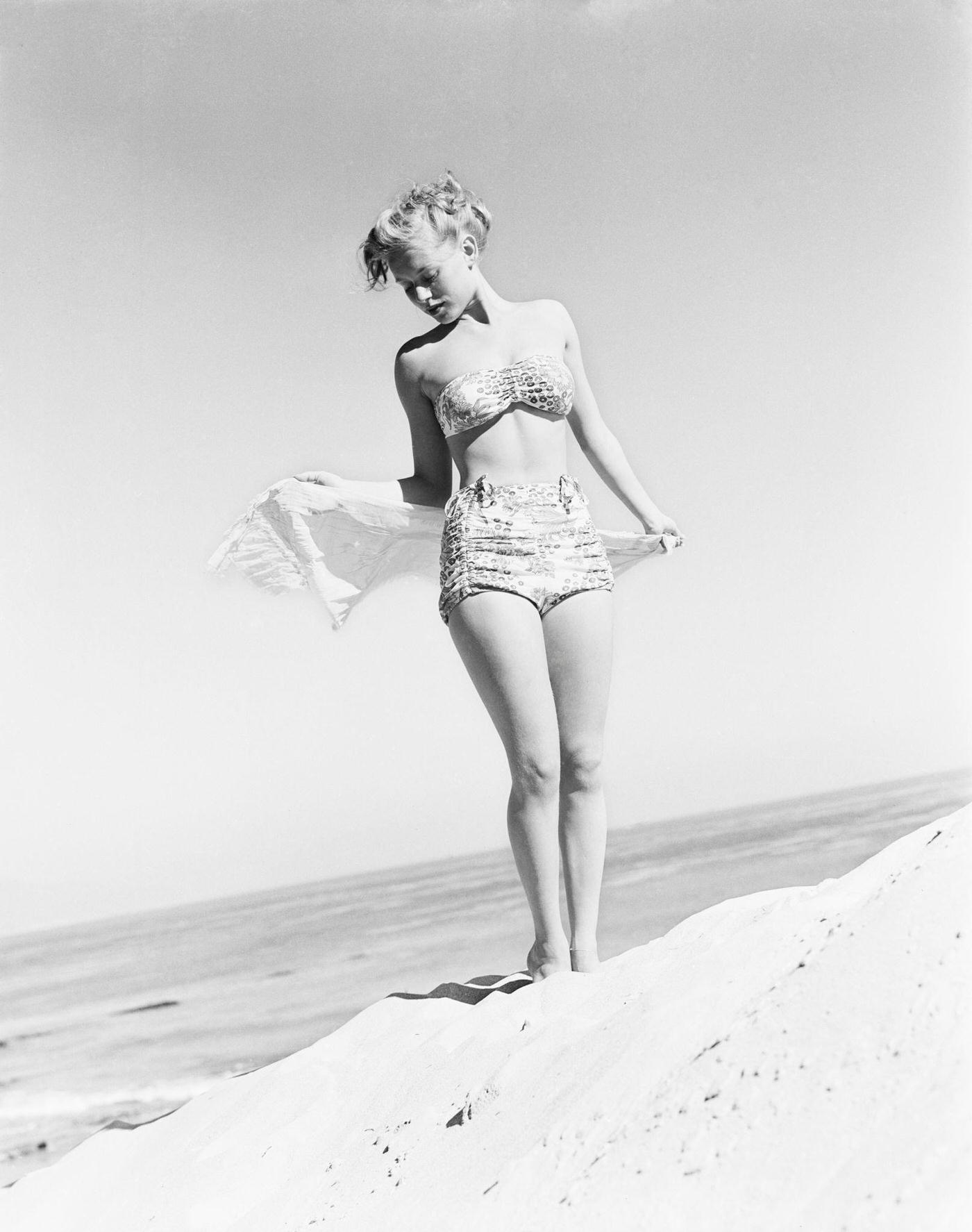 Model Fran Cooper wearing a patterned bikini on the beach, 1948.