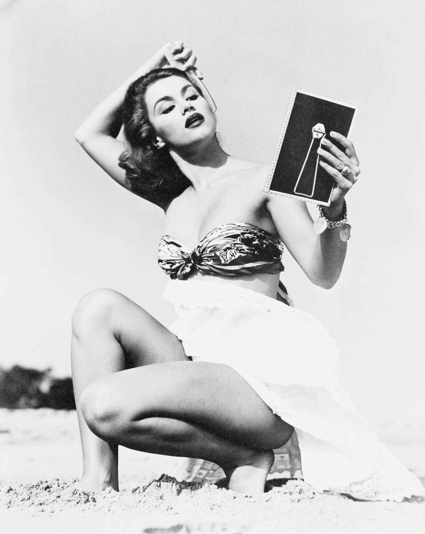 Young woman brushing her hair on the beach, 1948.