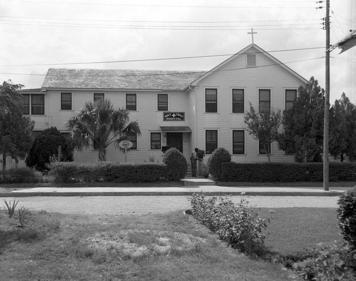 Holy Cross Hospital with Man Watering Yard, 1950.
