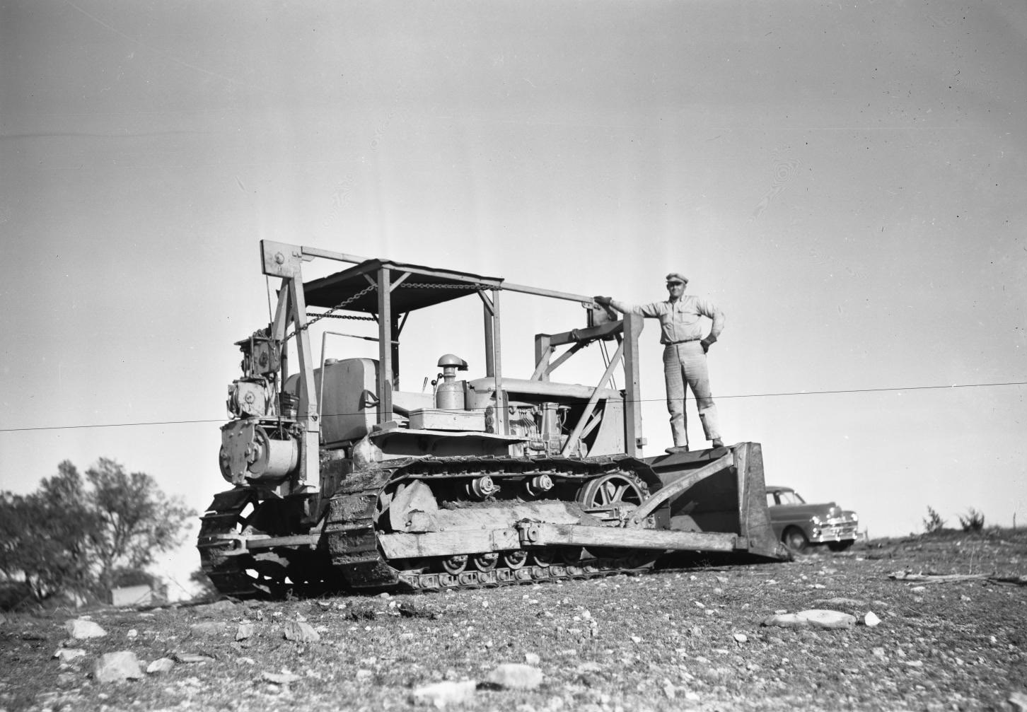 Man Standing on Tractor in Field, 1950.