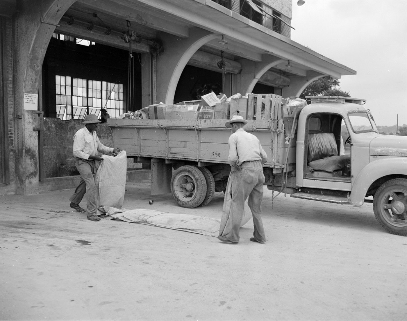 Men Folding Drape by Sanitation Truck, 1953.