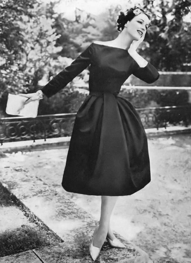 Betsy Pickering in black satin cocktail dress by Nina Ricci, 1957
