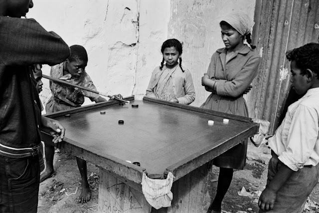 Hawking fresh vegetables, fruit, or fish, was big business in the area, and beyond. When not in use, hawkers' barrows were stashed along pavements. The wheels were removed to prevent unauthorised use or theft by rivals. District Six, Cape Town, South Africa.