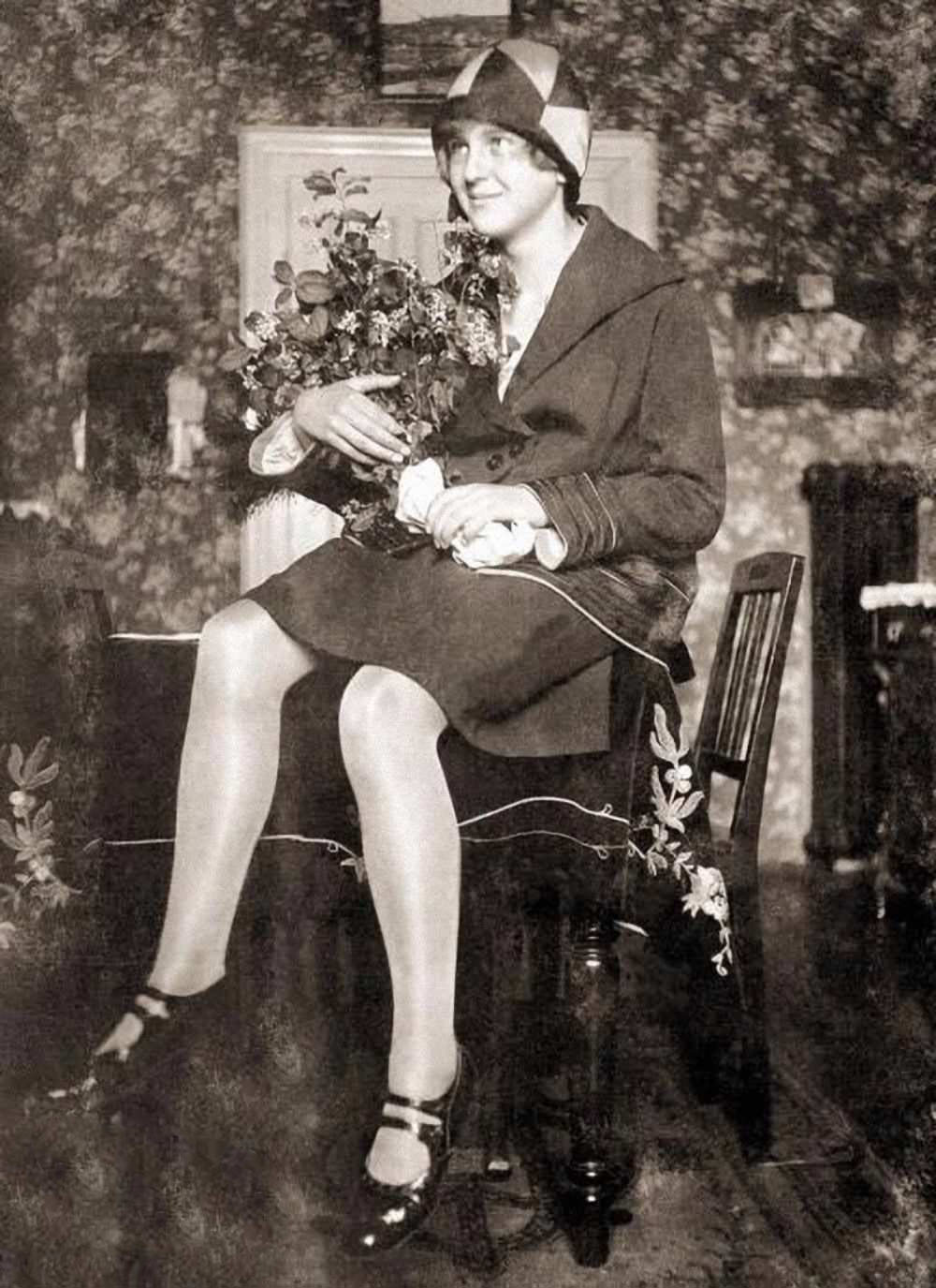 Eva Braun sitting on a table in the living room at her parent's house in Munich, Germany, 1929. She was staying with her family after finishing her education at a trade school; later that year, she met Hitler at Hoffmann's photo studio.