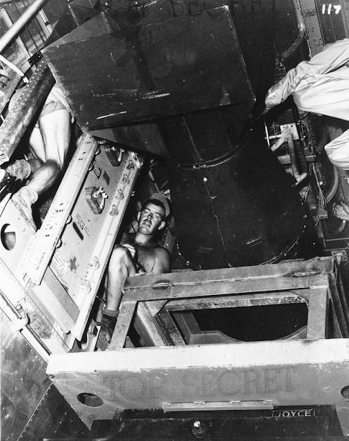 Little Boy has been successfully lifted into the bomb bay and is being attached to sway brackets that will keep it secure.