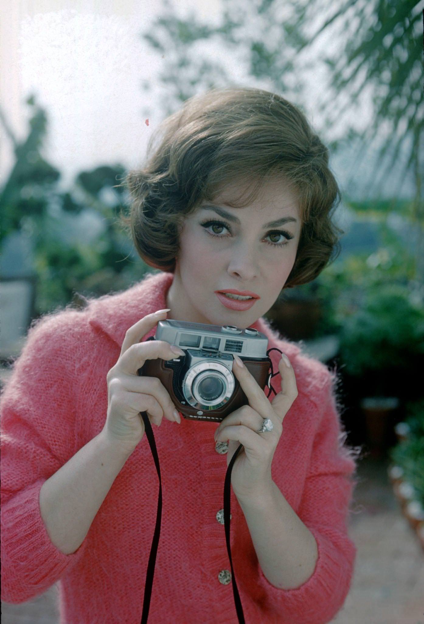 Gina Lollobrigida poses with a camera in Portofino, Italy, 1960.