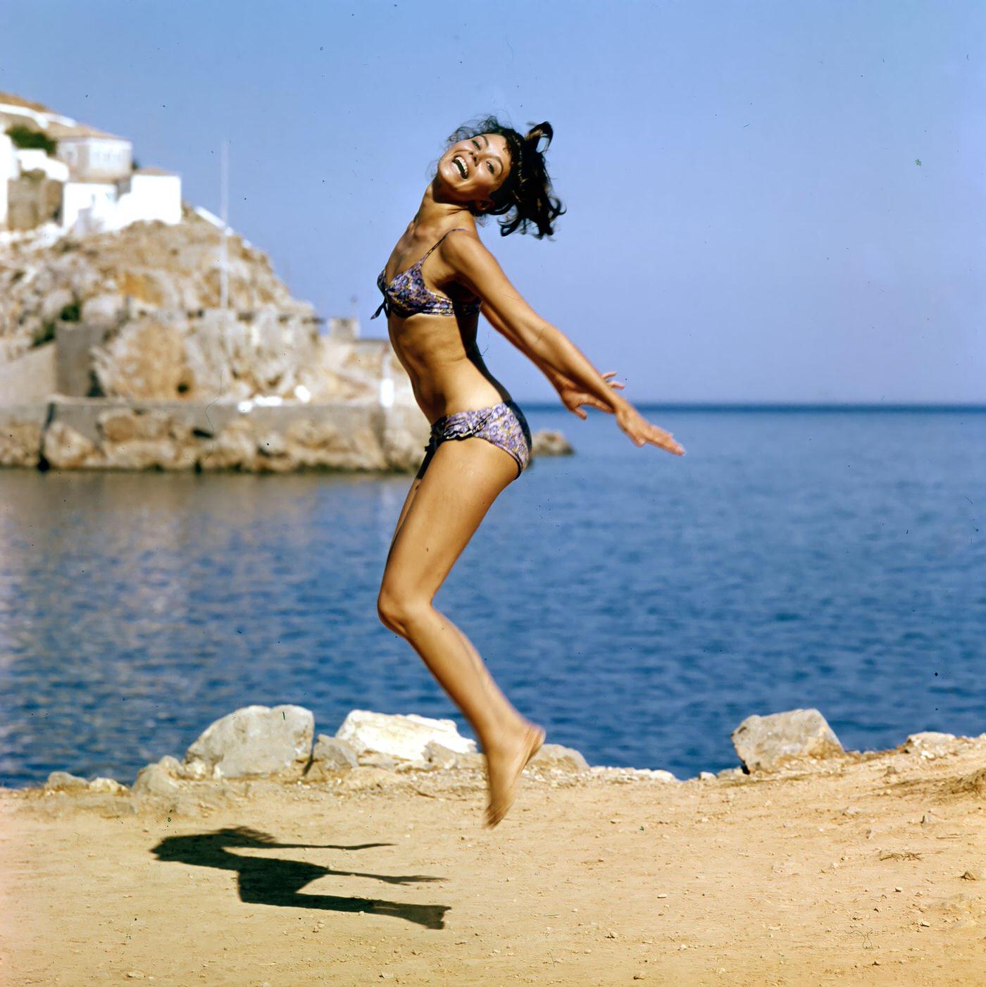 Giorgia Moll happily jumping at the beach, filming 'Island of Love,' Greece, 1962