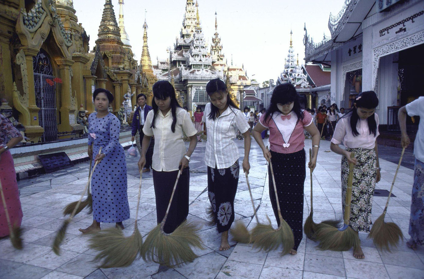 Barefooted Women Using Large Feather Dusters to Clean Sidewalk Outside of Shwe Dagon Pagoda