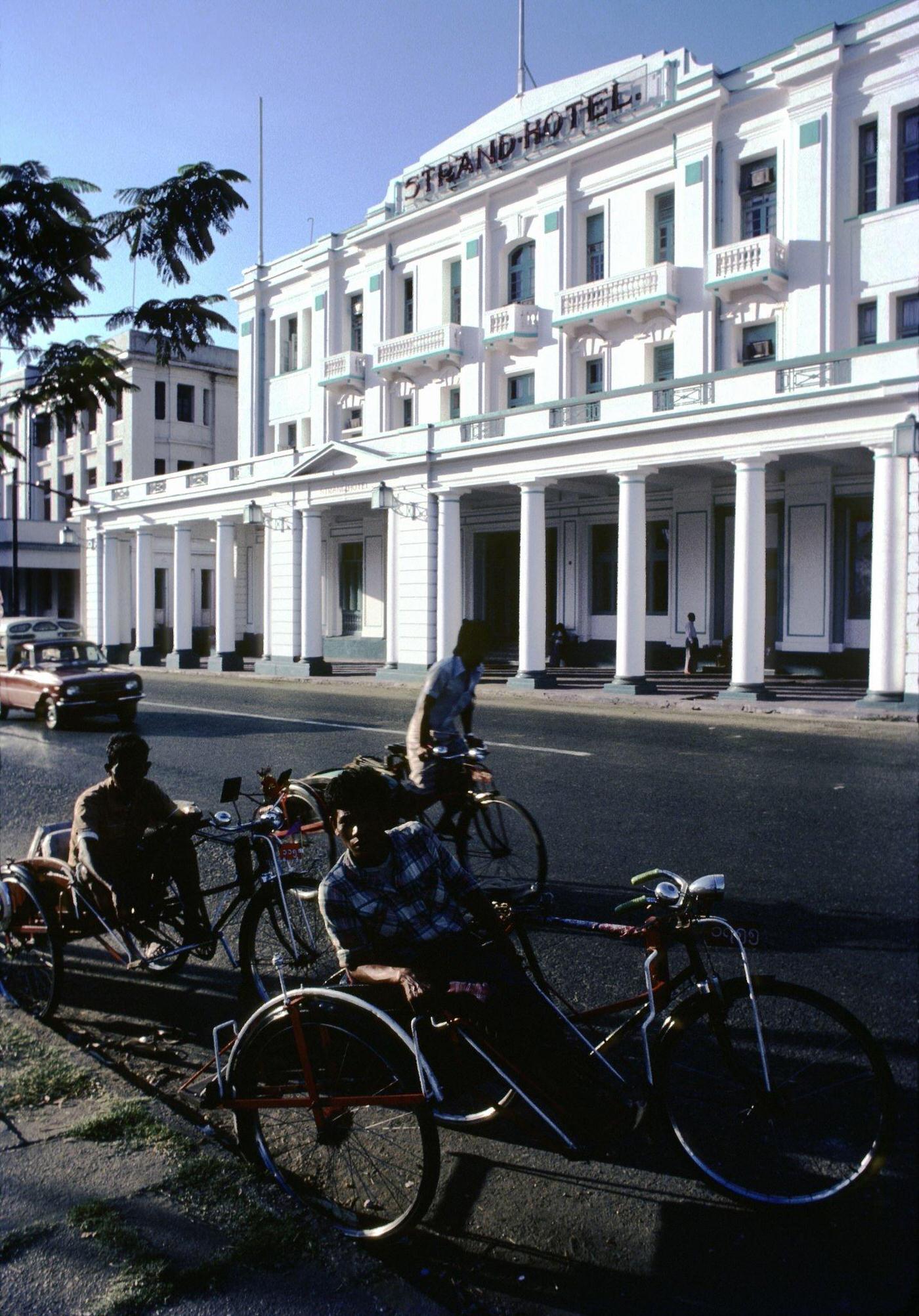 Three-Wheel Bicycle Taxis Wait Across the Street from the Strand Hotel in Central Rangoon, Burma, 1985