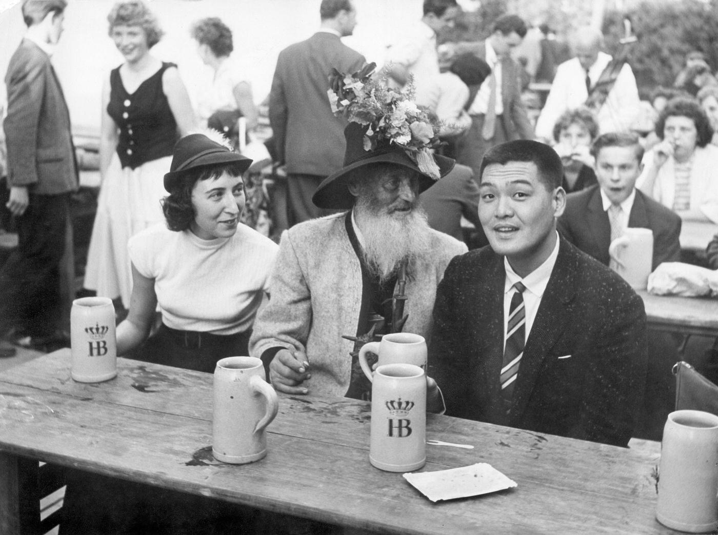 Japanese tourists enjoying Oktoberfest with Bavarians, 1960.