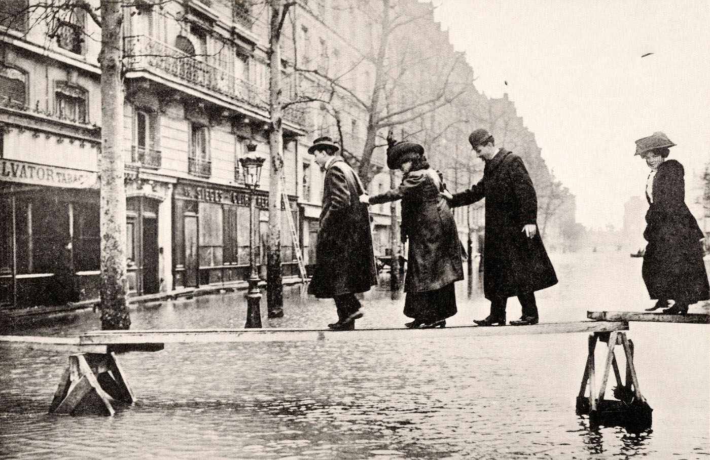 Vintage French postcard: pedestrians crossing flooded Seine River at Avenue Ledru-Rollin, Paris, circa January 1910.
