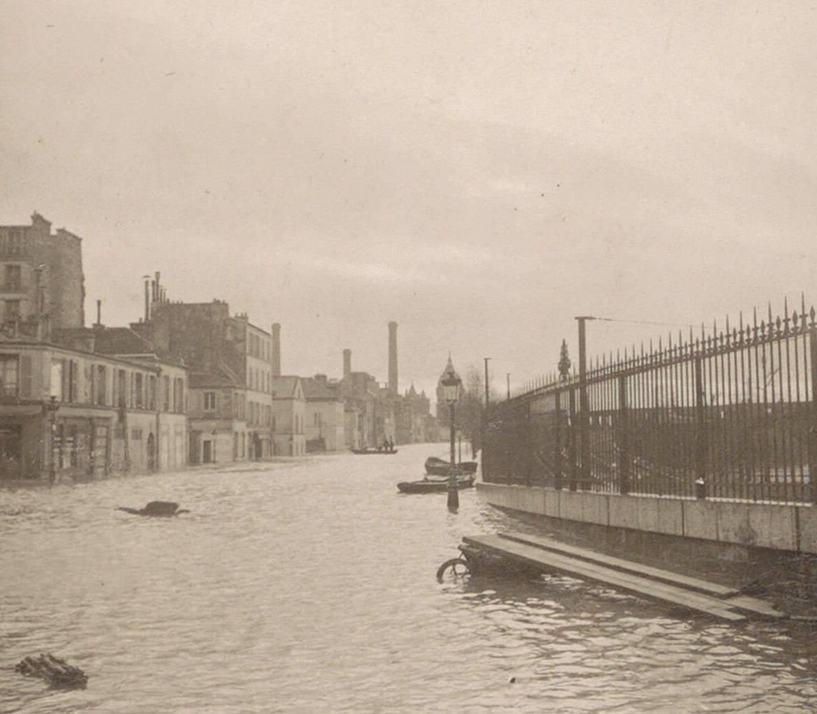 Flooded street with a fence during Paris flood. Part of photo album flooding Paris and suburbs 1910.