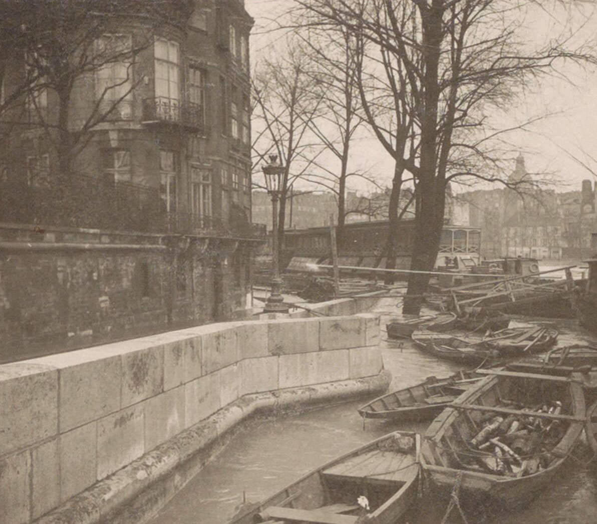 Boats along a quay during Paris flood. Part of photo album flooding Paris and suburbs 1910.