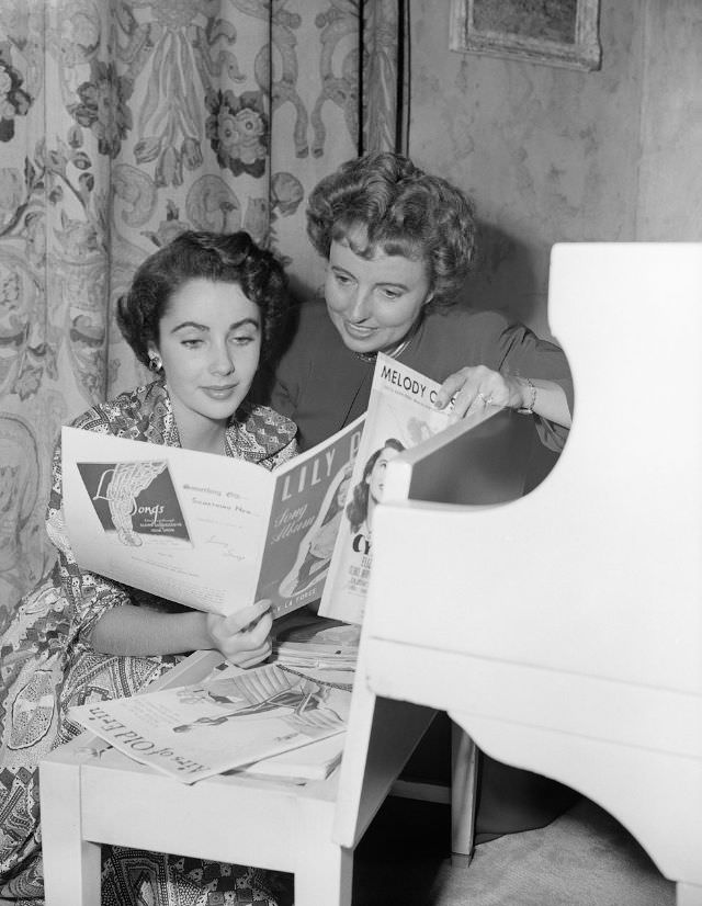 Sara Sothern and her daughter Elizabeth Taylor look over sheet music at the piano in their Beverly Hills home, 1949