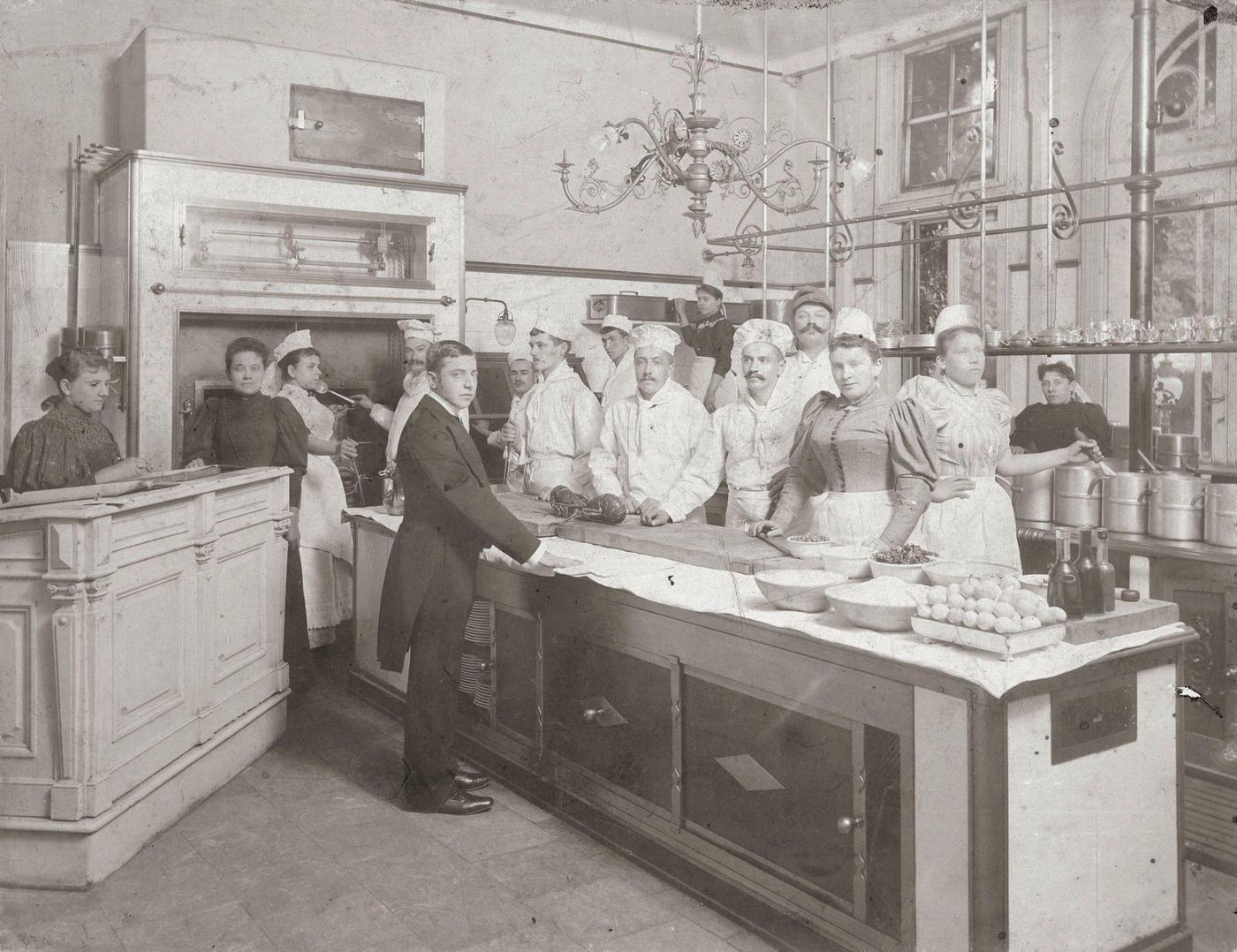 Kitchen of a restaurant in the city: 2 ovens, 2 skewers, cooks (with lobster), kitchen staff, waiter, accountant, Vienna