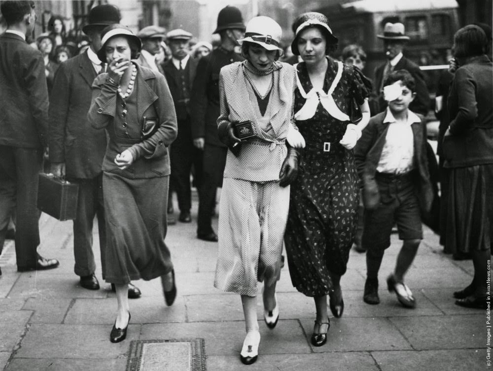 Brenda Dean Paul (1907–1959, centre) leaves court after facing drugs charges, July 1933. She is holding a tin of large Sub Rosa cigarettes.