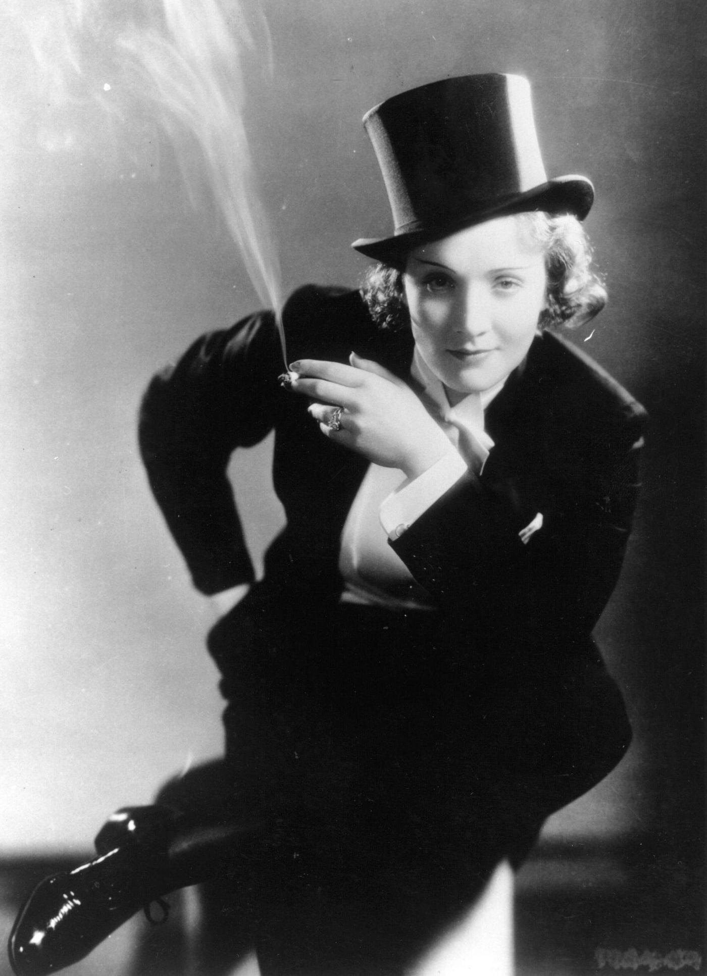 German-born American film star Marlene Dietrich dressed in men's top hat and tails and smoking