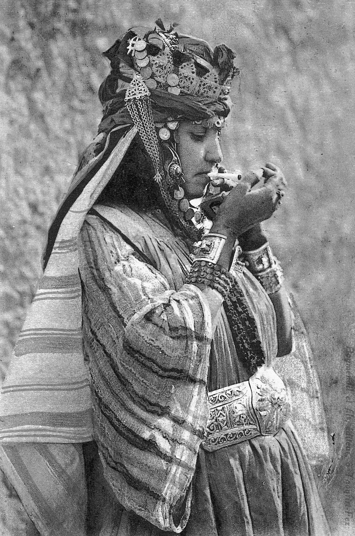 Traditional dressed Moroccan woman smoking a cigarette, 1930.