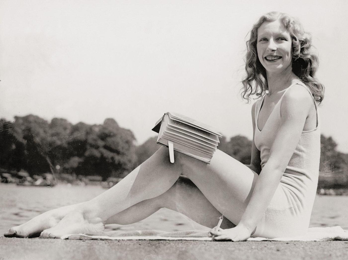 Sunbathing girl in her bathing suit in Hyde Park, London, smoking a cigarette and reading a book, 1932