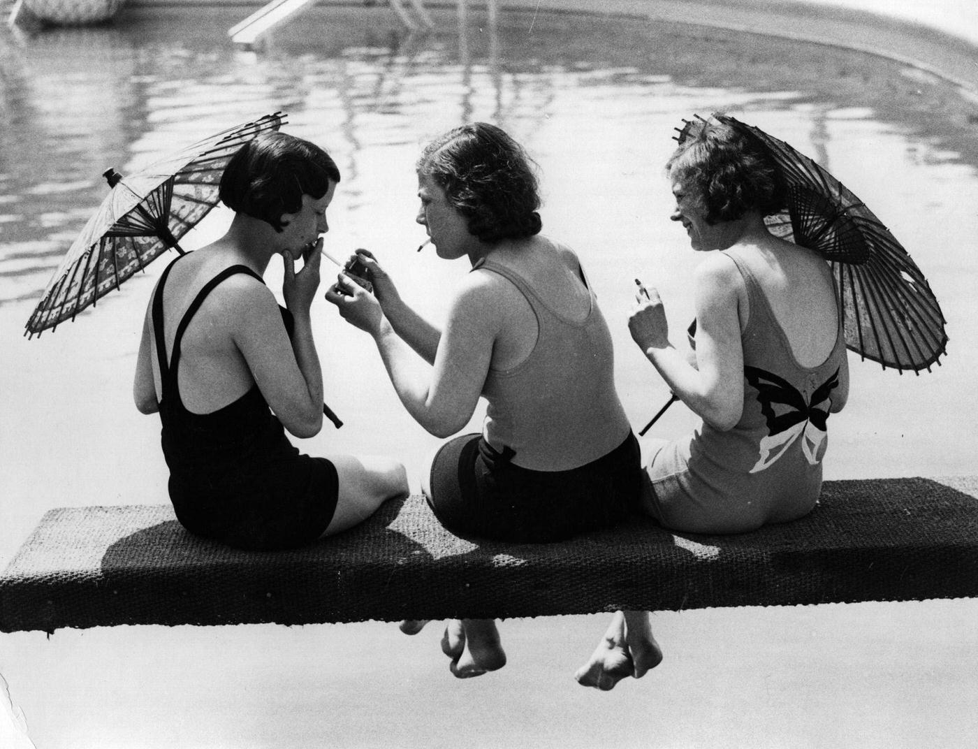 A group of women light up their cigarettes while relaxing on a diving board at Cliftonville