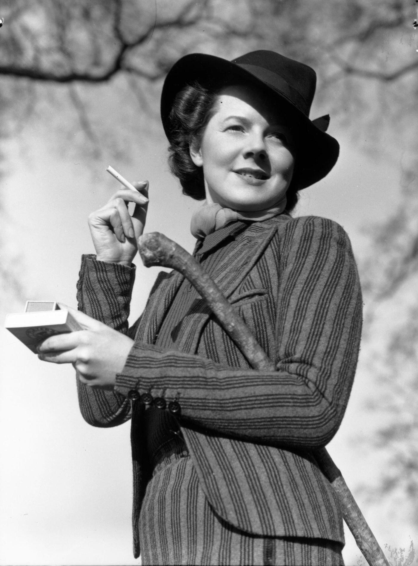 A woman about to light a cigarette after a bracing walk, 1935