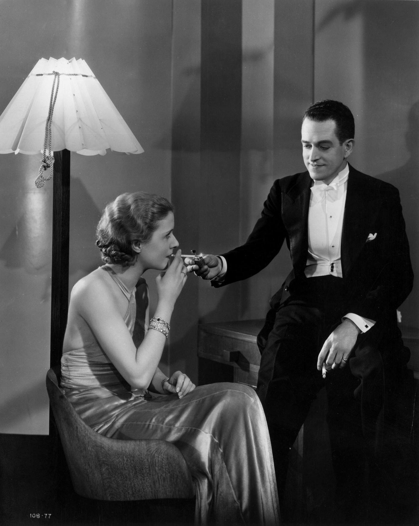 Molly Lamont accepts a light from Gene Gerrard in a scene from 'Lucky Girl', 1935