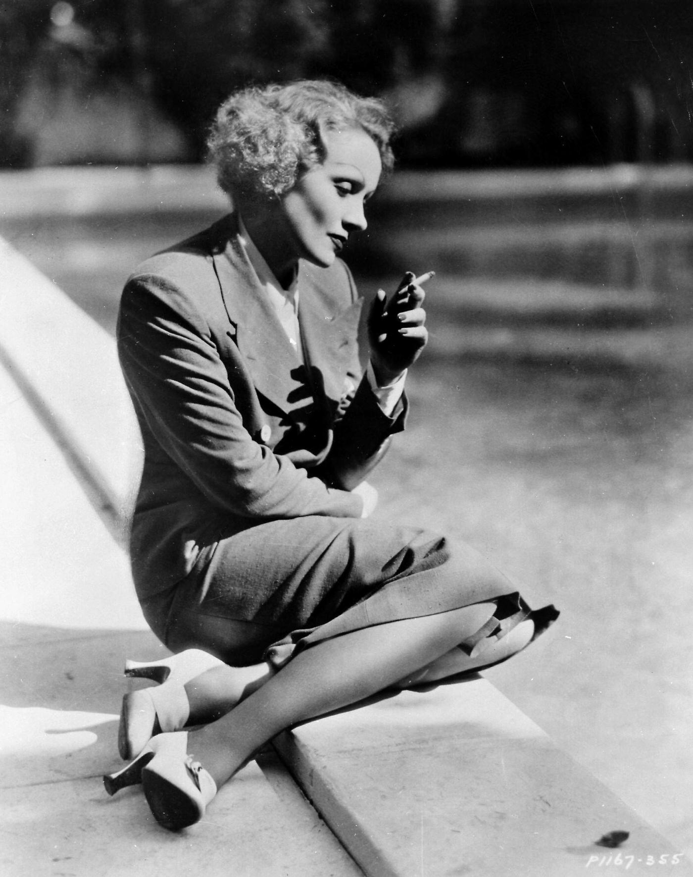 German born actress Marlene Dietrich smoking by her swimming pool in Beverly Hills, 1930s