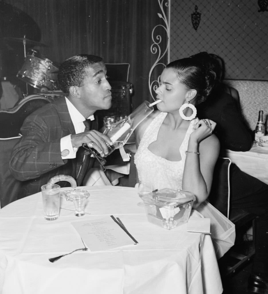 American actor Sammy Davis Jnr at a candlelit dinner for two, without visible cigarettes, circa 1950.