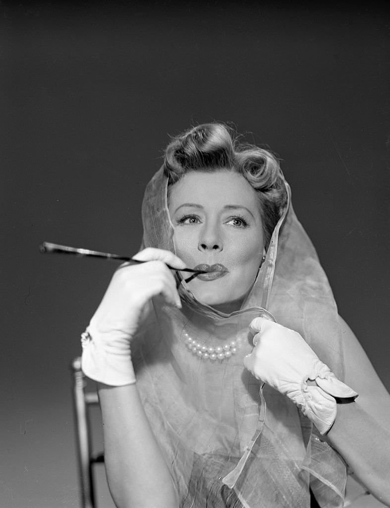 Actress Irene Dunne smoking a cigarette in character for "Port of Call" episode of "The Schlitz Playhouse of Stars," California, 1952.