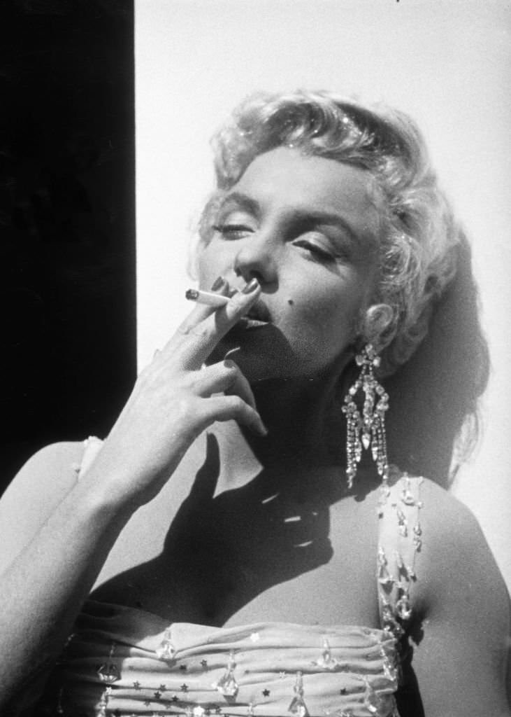 Marilyn Monroe smoking a cigarette on the set of "There's No Business Like Show Business," 1954.