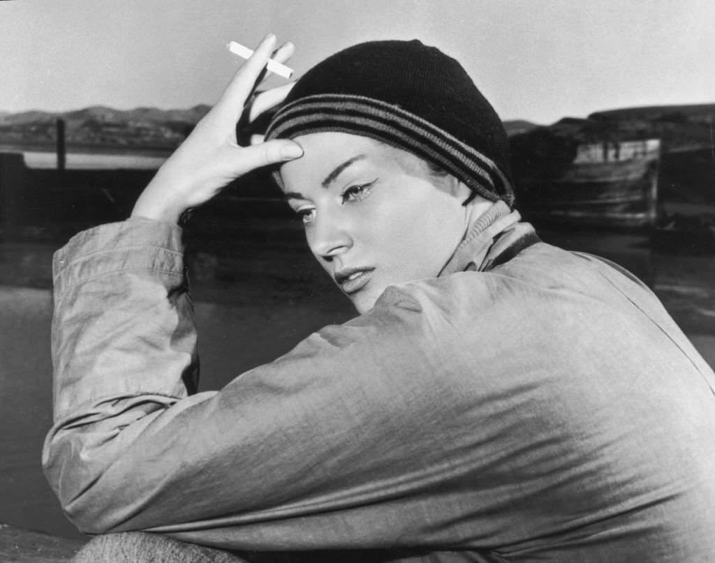 Swedish-born actor Anita Ekberg smoking a cigarette on the set of William Wellman's film 'Blood Alley', 1955.