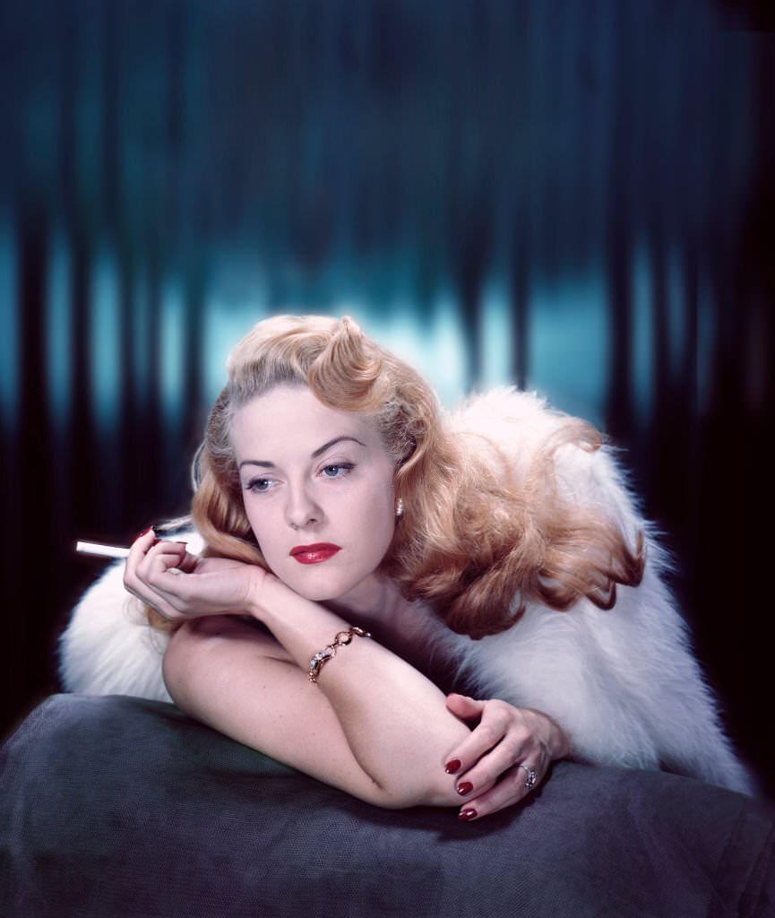 Close-up portrait of a fashion model smoking under a fur wrap, 1955.