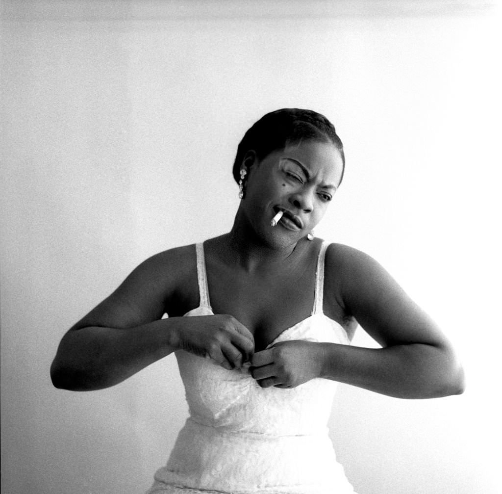 American singer LaVern Baker smoking and adjusting her dress in New York, New York, 1957.