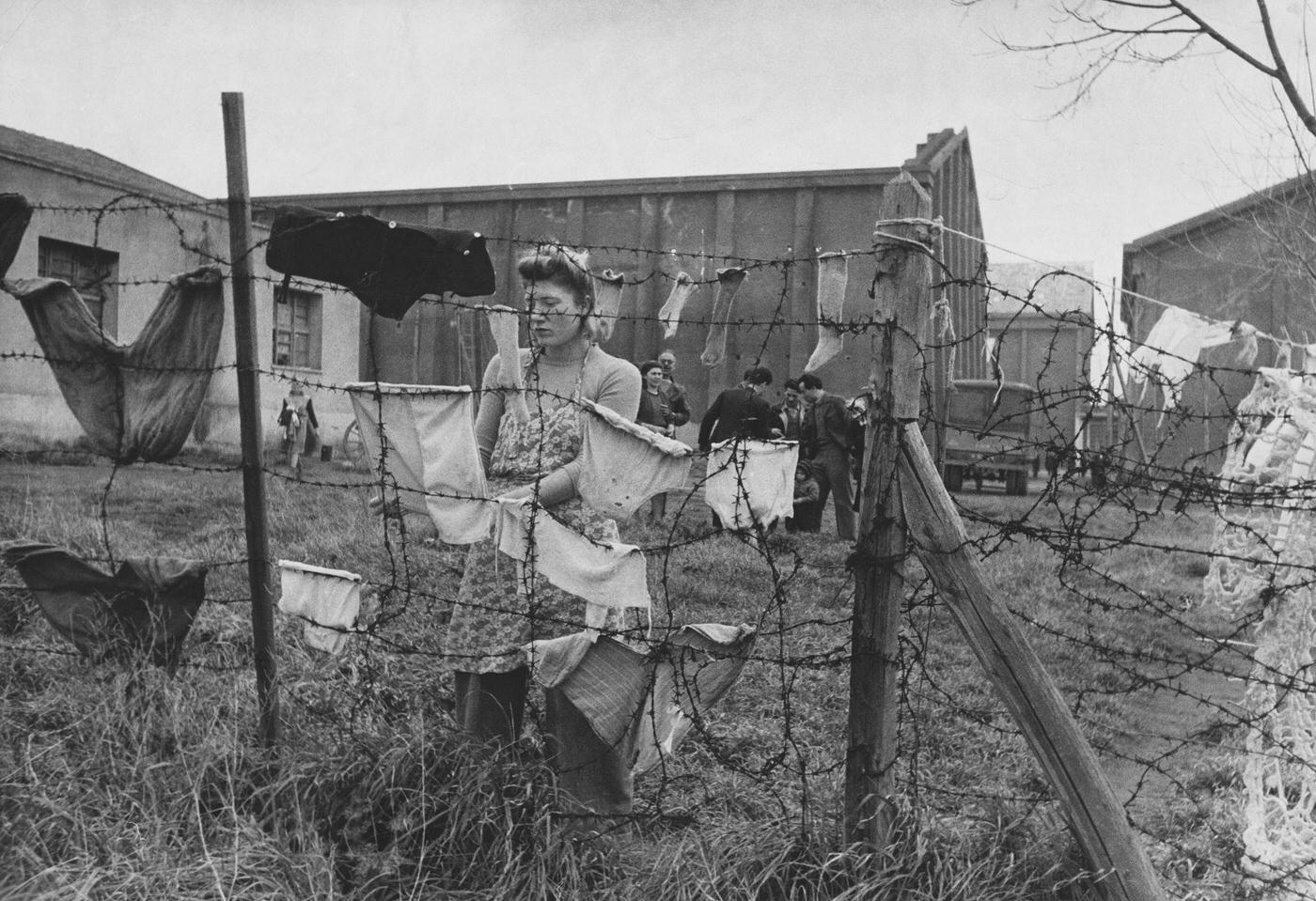 Italian Woman Refugee Hangs Laundry on Barbed Wire Fence in Rome, Year Unspecified