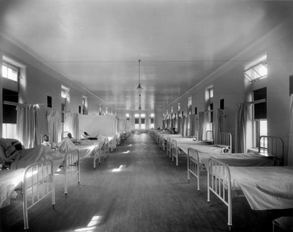 Men in a ward of Denver General Hospital with empty beds and curtains, 1900s