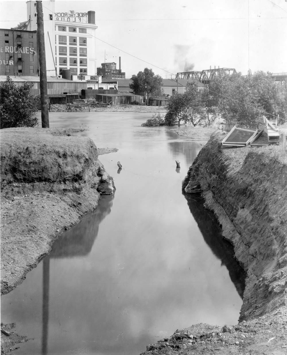 Construction site near South Platte River, featuring Pride of the Rockies Flour Mill and 20th Street Viaduct, 1900s