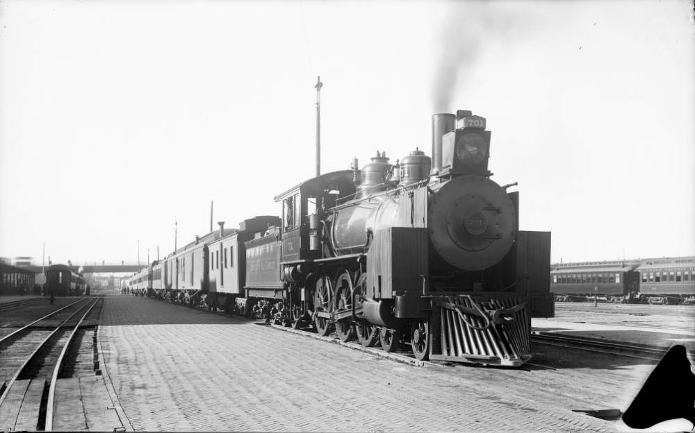 Denver and Rio Grande Railroad engine No. 701 arrives at Union Station with a view of tracks and buildings, 1900s