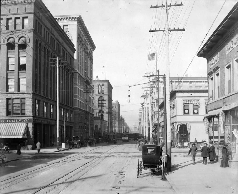 Denver Tramway trolleys at the intersection of 17th and California, featuring various businesses and pedestrians, 1905.