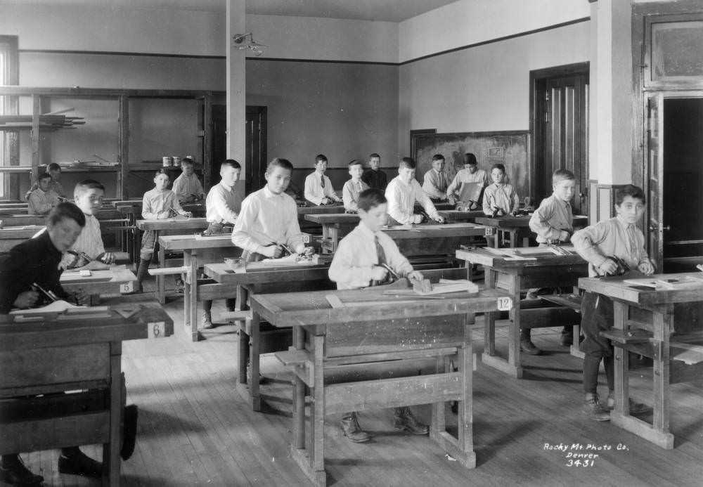 Boys in a woodworking workshop at Denver Orphans' Home, showcasing worktables and lumber racks, 1900s