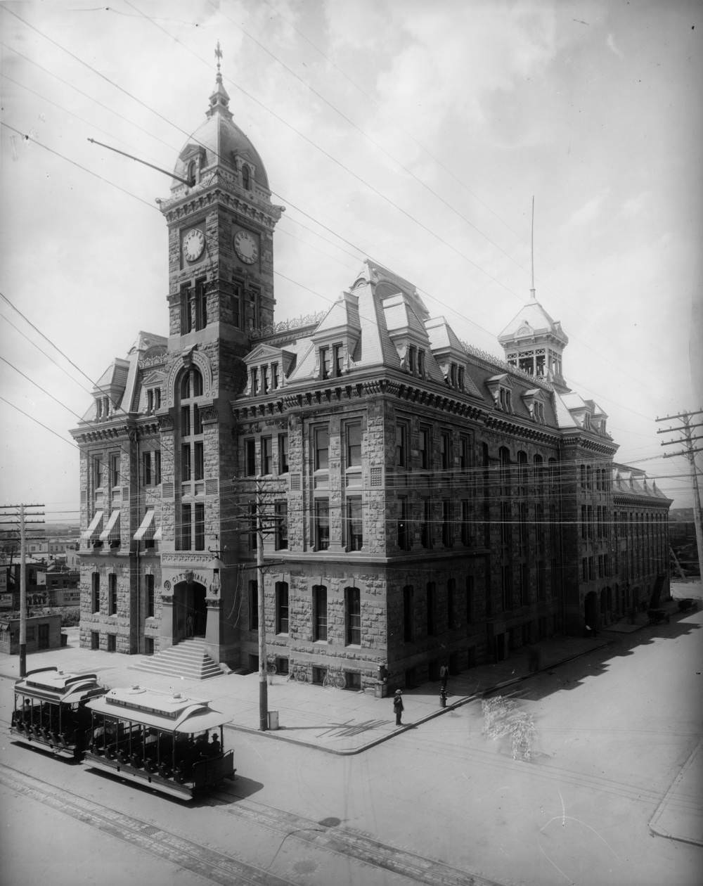 Denver City Hall on 14th Street, featuring a trolley car and bicycles, 1900s